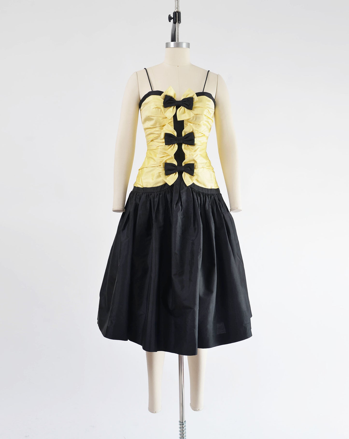 Vintage 80s yellow and black dress with spaghetti straps. Dropped waist with full skirt. Three bows on front.