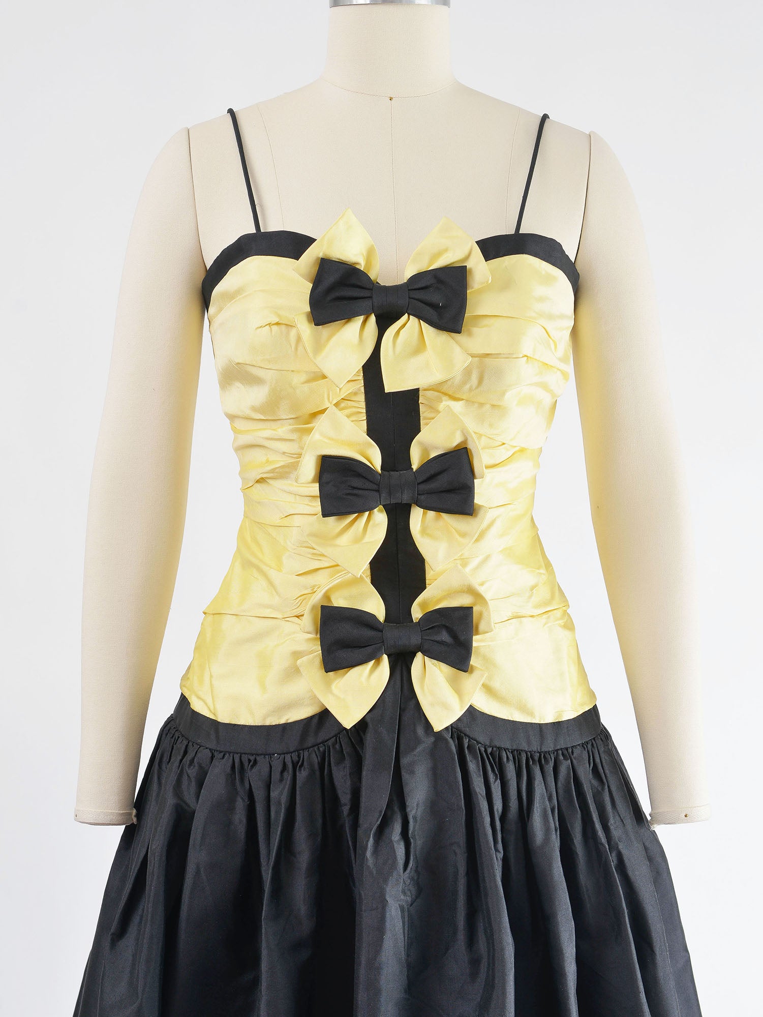 Bodice of yellow and black dress with three bows down the front.