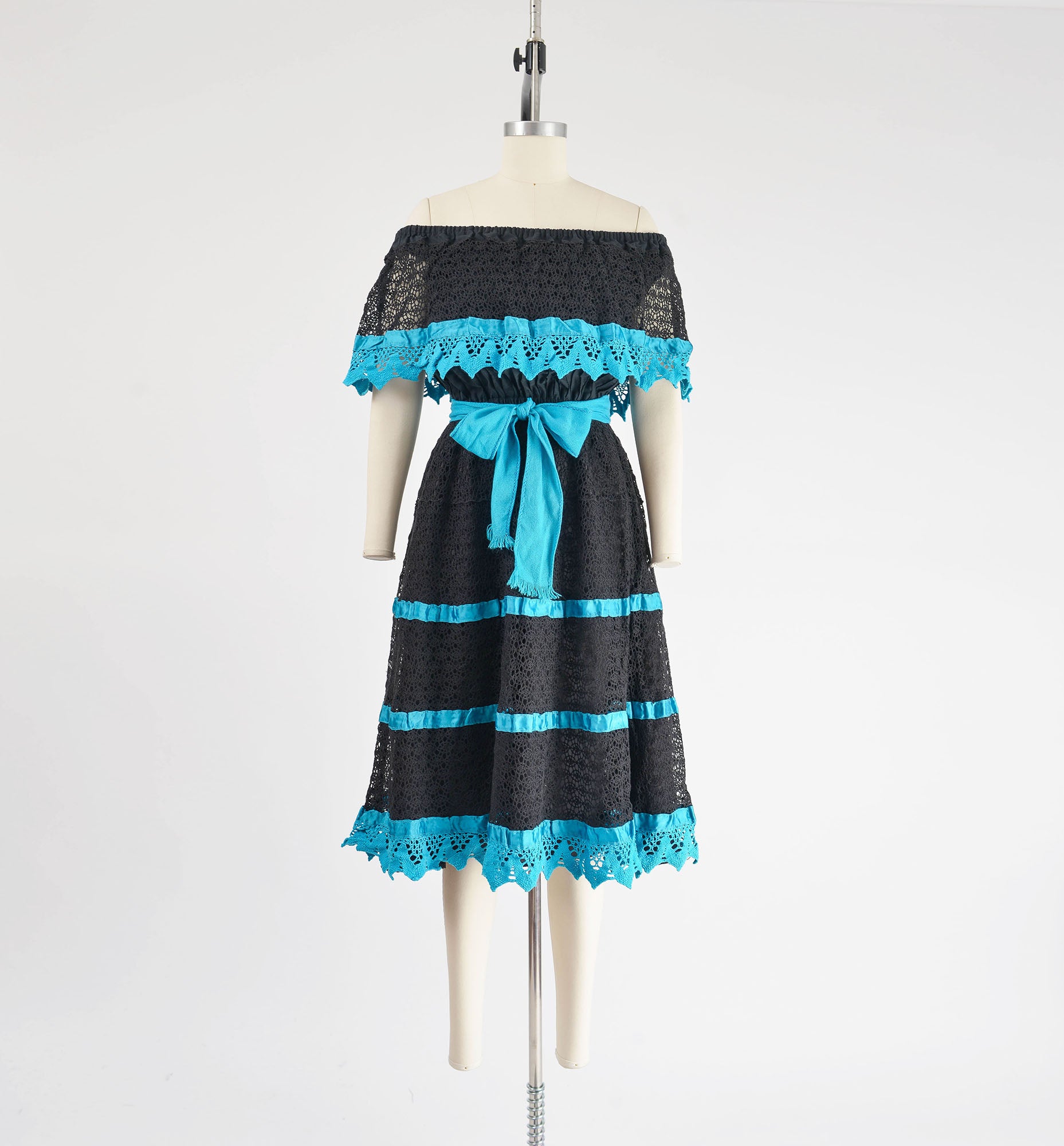 Full view of 1980s black and blue sheer lace Mexican dress with off shoulder neckline.