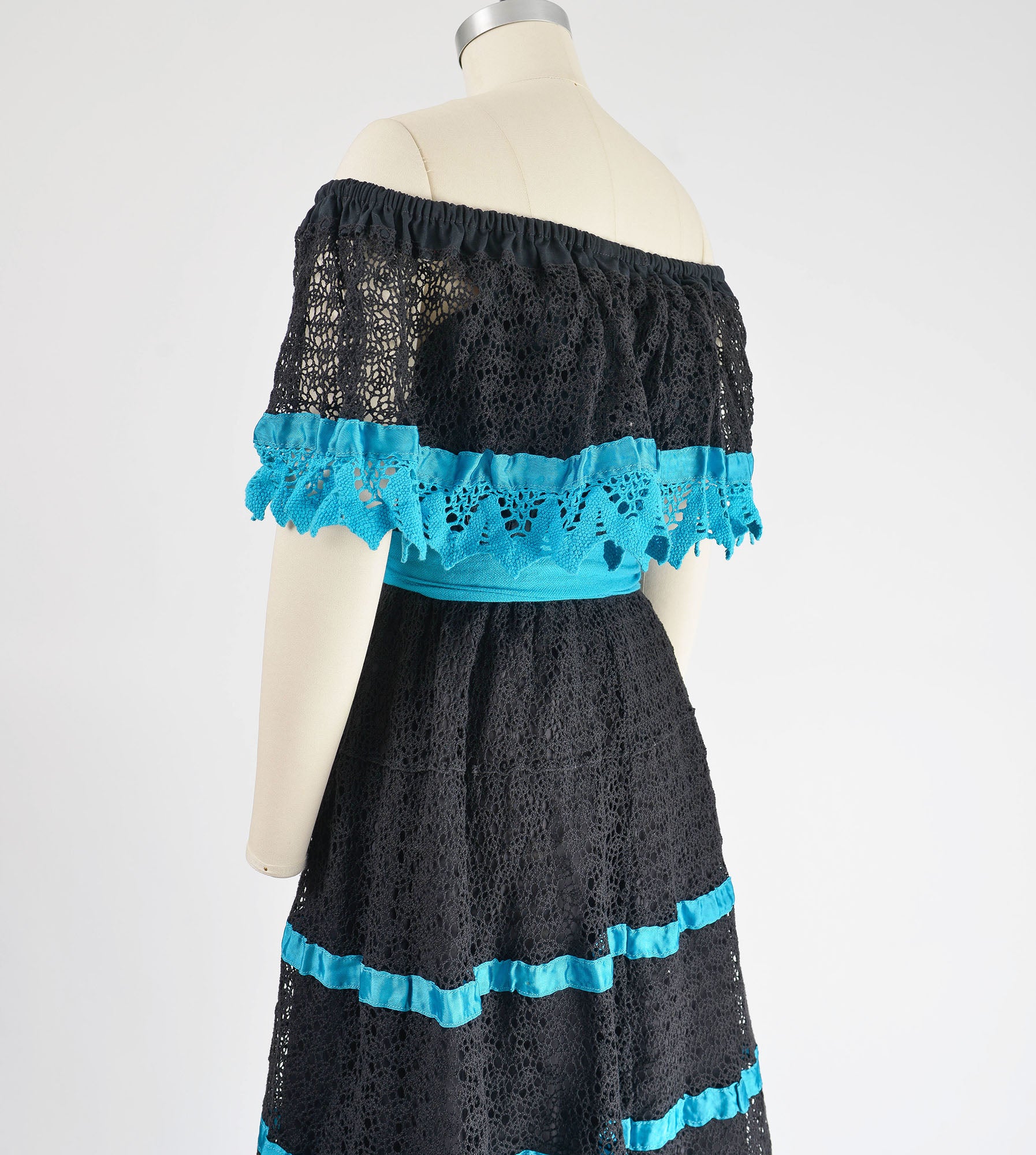 Side back view of 1980s black and blue sheer lace Mexican dress with off shoulder neckline.