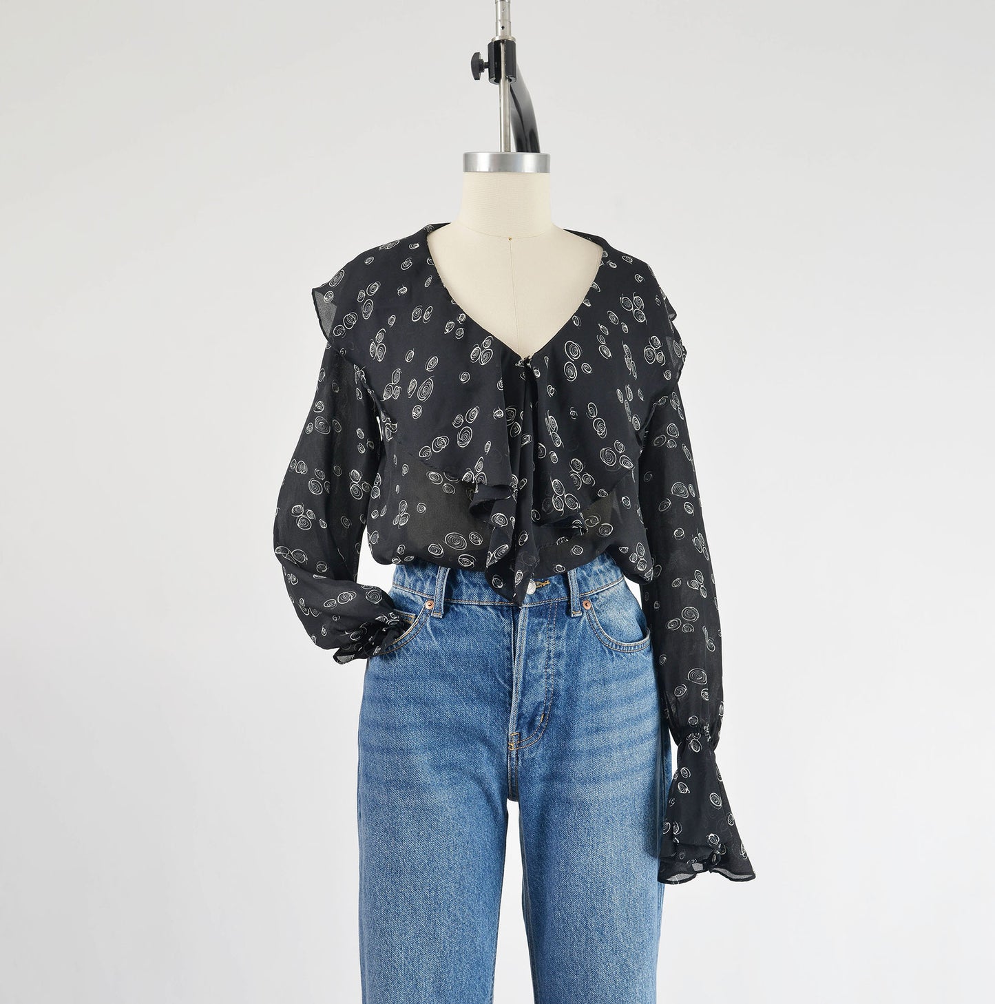 Vintage Black and white sheer poet blouse with ruffle neckline styled with sleeve tucked into jean pocket.