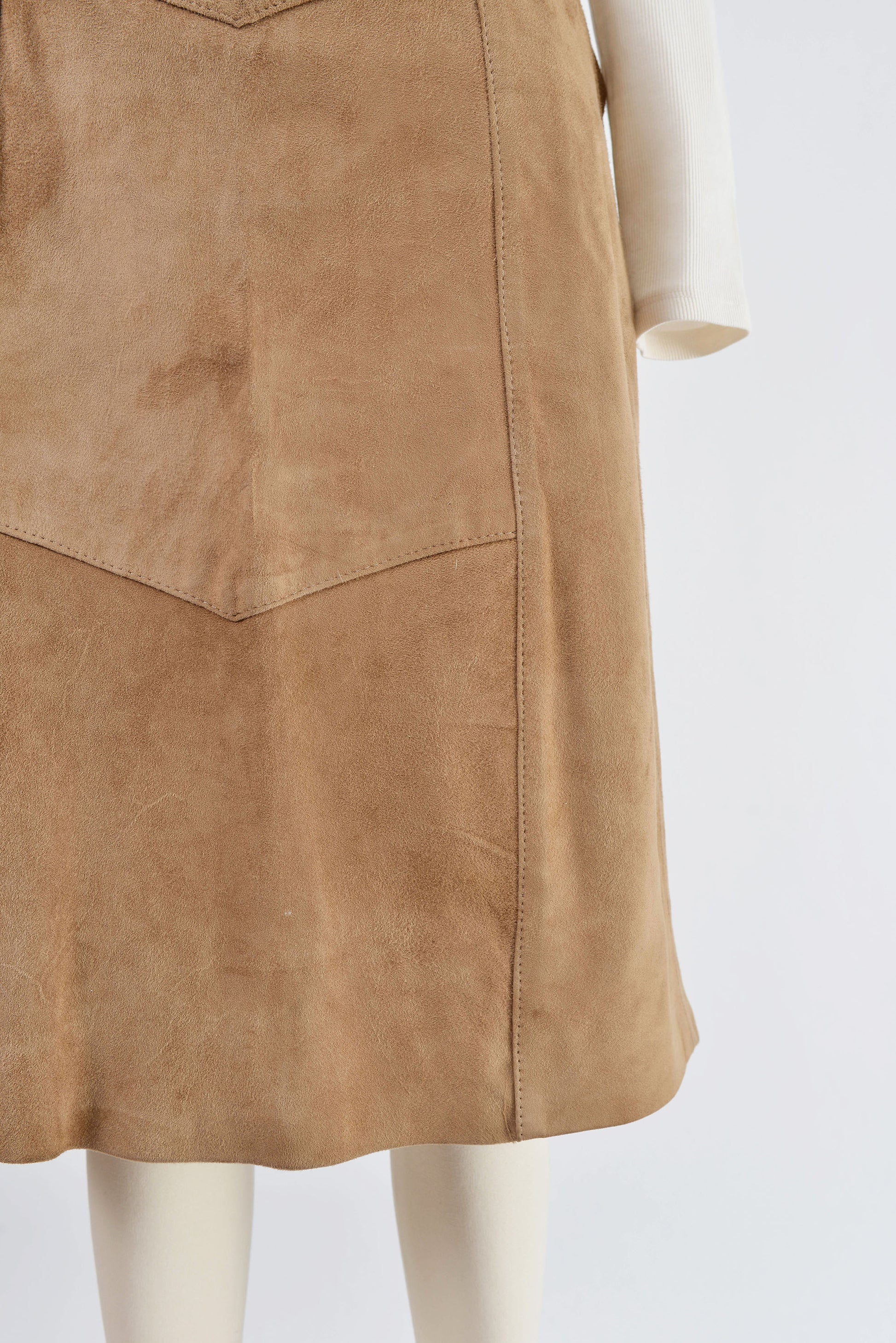 Close up view of hemline on 70s light brown suede skirt.