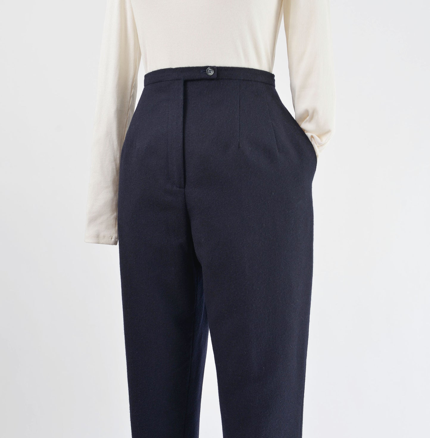 View of navy wool pants with shirt sleeve tucked into one pocket.