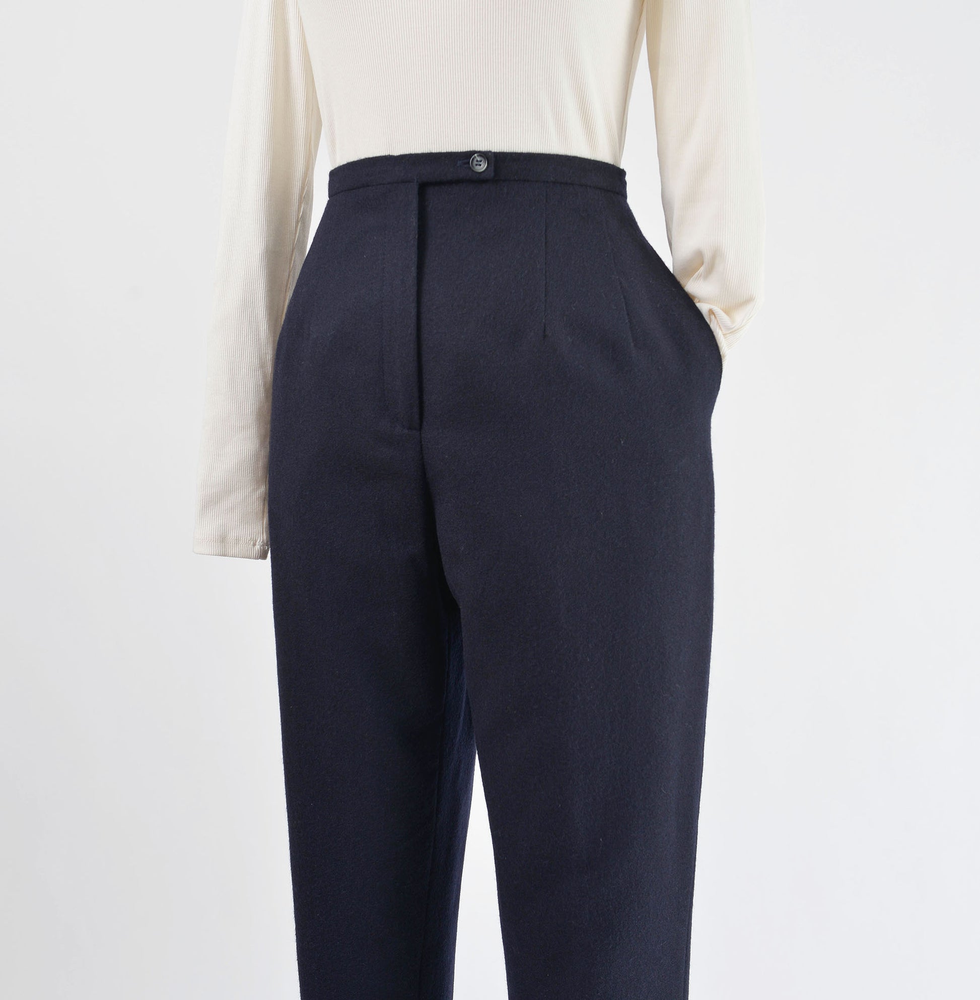 View of navy wool pants with shirt sleeve tucked into one pocket.