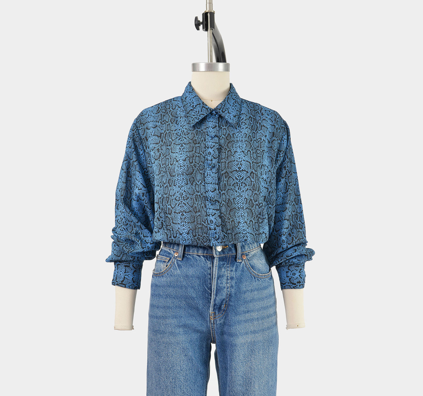 Full front view of vintage 90s blue snakeskin print blouse. Semi sheer fabric. Button down front. Style tucked into jeans.