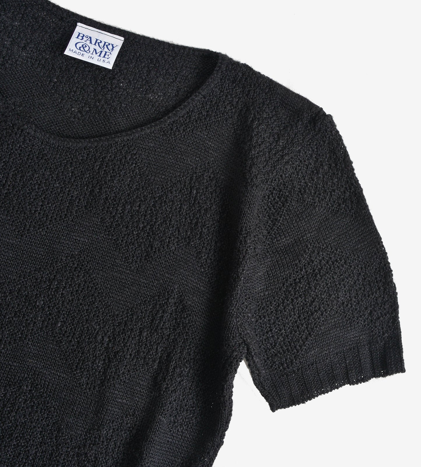 Close up flat view of 80s black short sleeve sweater.