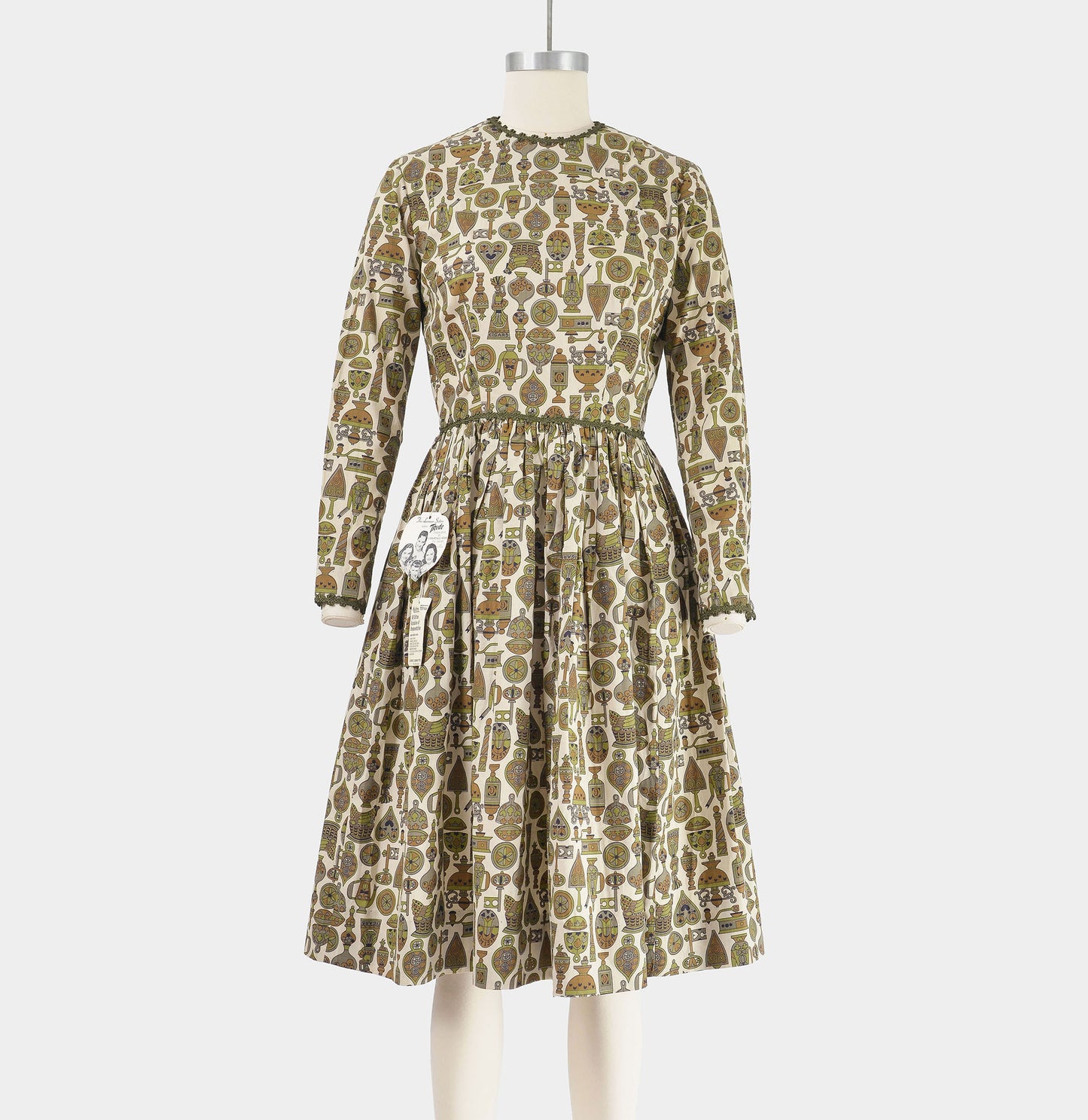 Front view of vintage 1960s tan and green novelty print dress with full gathered skirt. 