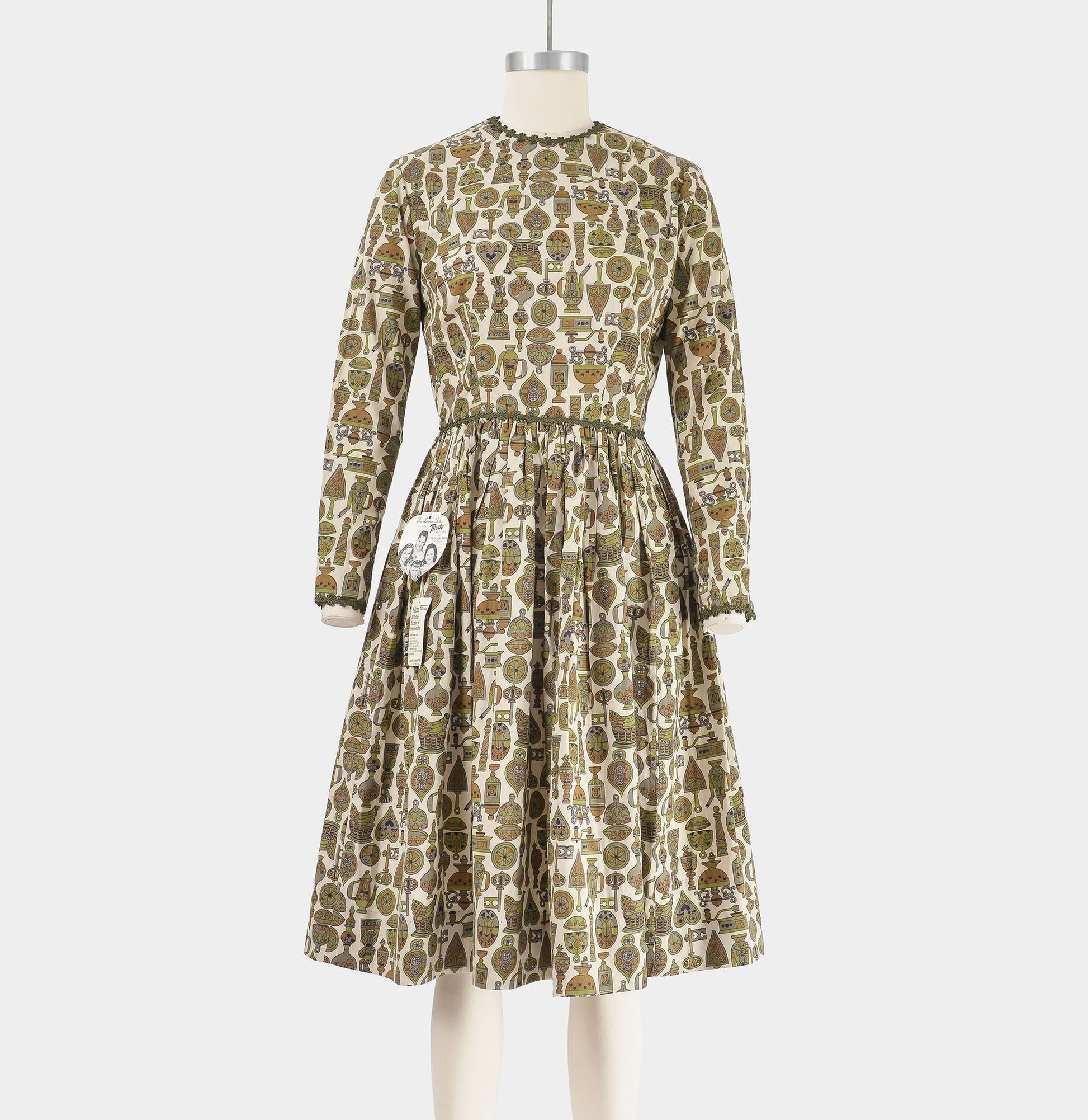 Front view of vintage 1960s tan and green novelty print dress with full gathered skirt. 