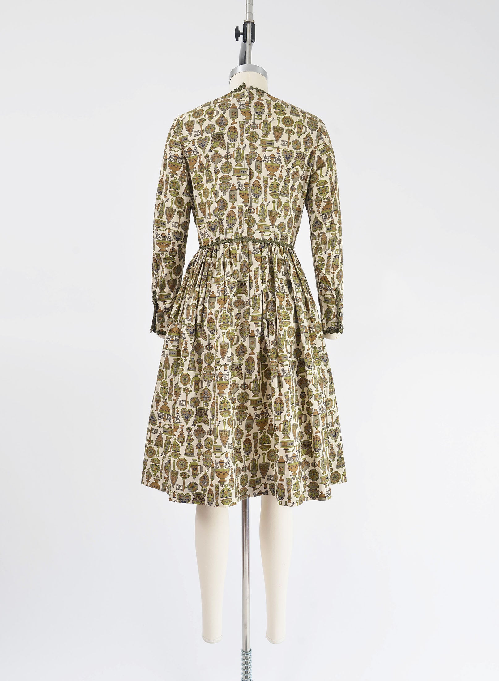 Full back view of vintage 1960s tan and green novelty print dress with full gathered skirt.