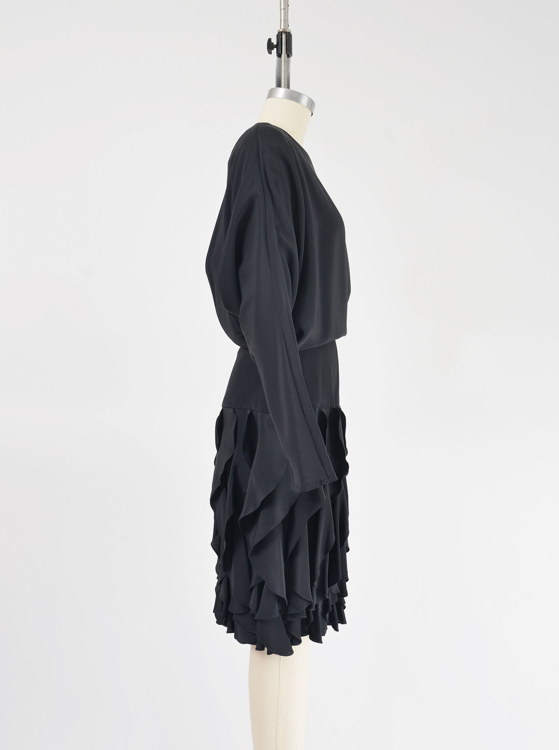 Side view of Vintage 80s black batwing sleeves dress with flounce ruffle skirt.