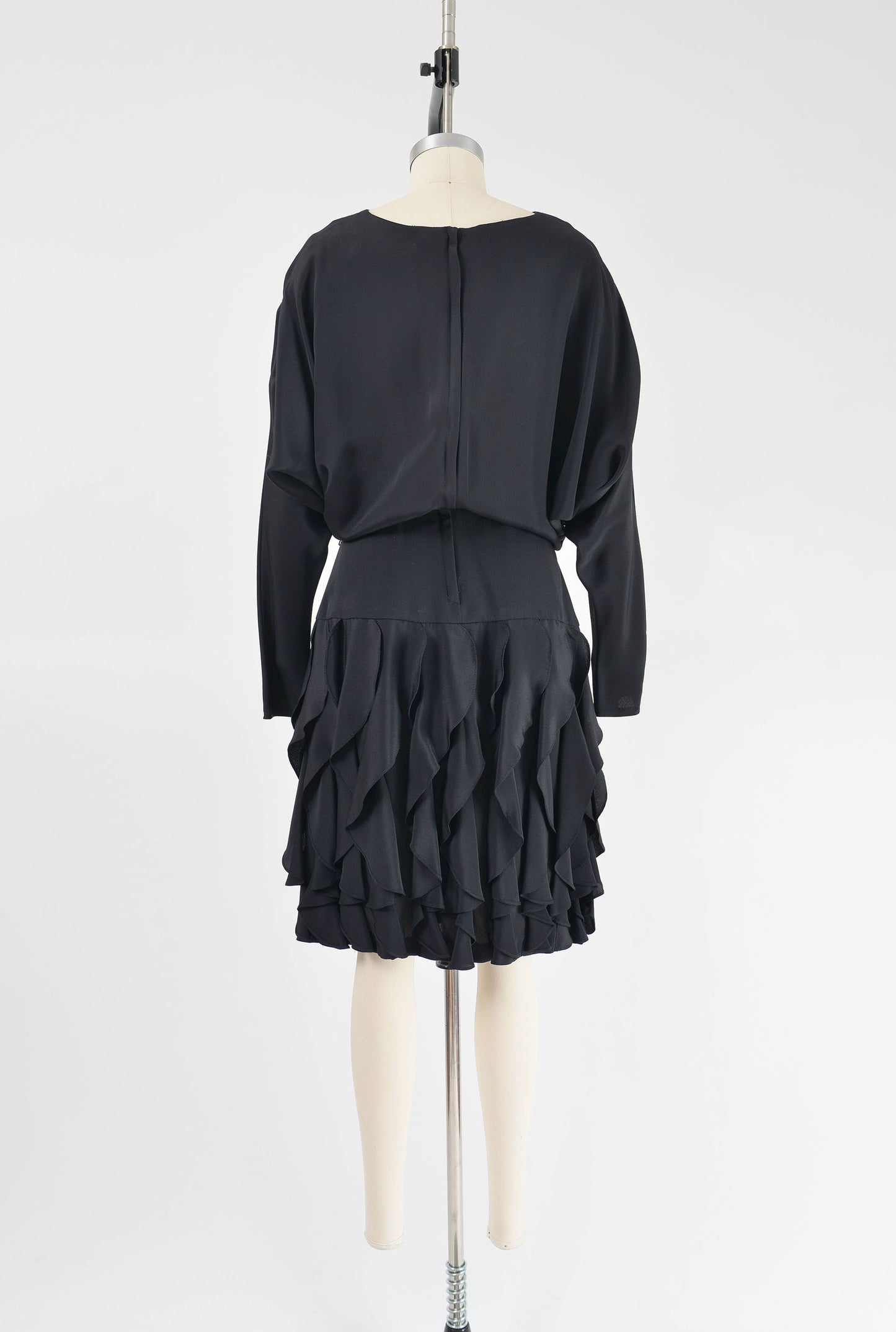 Full back view of vintage 80s black batwing sleeves dress with flounce ruffle skirt.