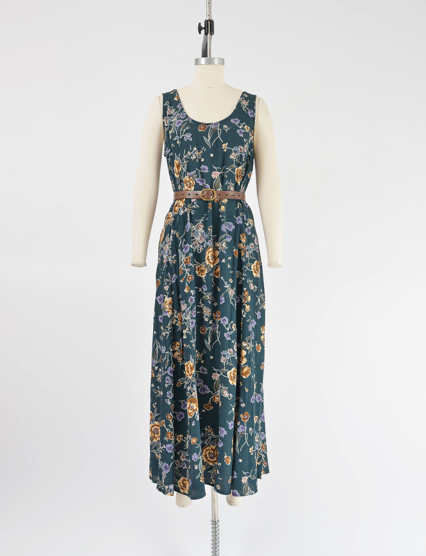 Full front view of Vintage 90s dark green floral print sleeveless maxi dress. Belted in image.