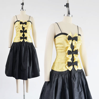 Vintage 80s yellow and black dress with spaghetti straps. Dropped waist with full skirt. Three bows on front.